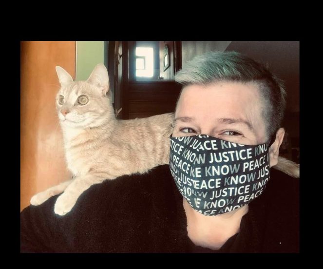 blonde DSH cat on shoulder of J9, green & black hair, pale skin, wearing a "NO JUSTICE NO PEACE, KNOW JUSTICE KNOW PEACE" mask